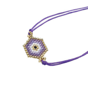 Beaded purple and gold eye pendant on a purple cord necklace, close-up.