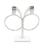Pair of large silver hoop earrings displayed on a white stand.