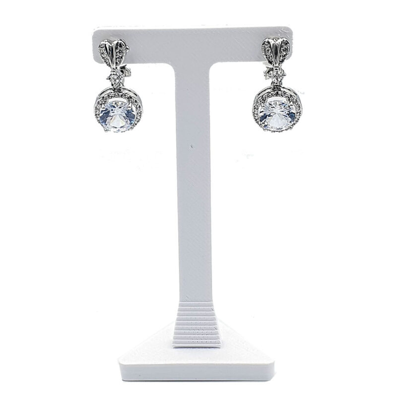 Pair of silver drop earrings with round clear stones on a white display stand, jewelry product photo
