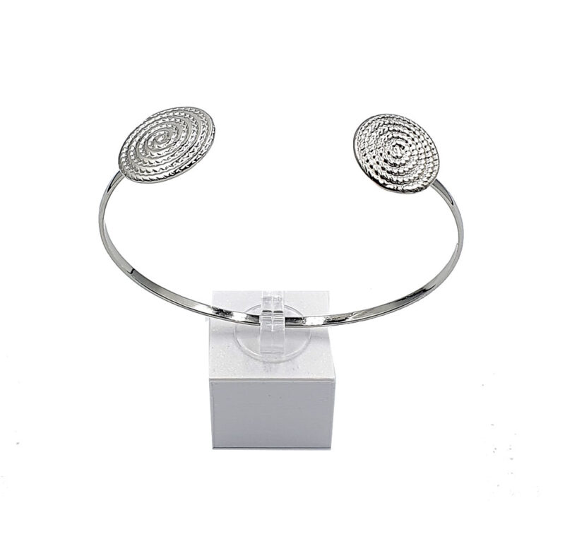 Silver-toned open cuff bracelet with two textured circular ends, displayed on a small white pedestal.