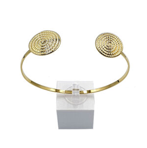 Gold-tone open cuff bracelet with two textured spiral discs on each end, displayed on a clear stand.