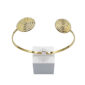 Gold-tone open cuff bracelet with two textured spiral discs on each end, displayed on a clear stand.