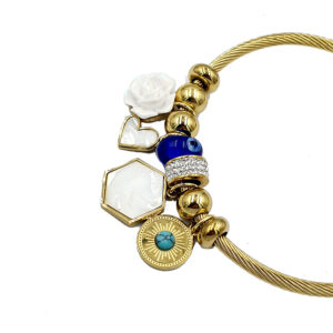 Gold bracelet with assorted charms: white rose, open heart, hexagonal white gem, blue bead, turquoise inlay, rhinestone band, and sun medallion.