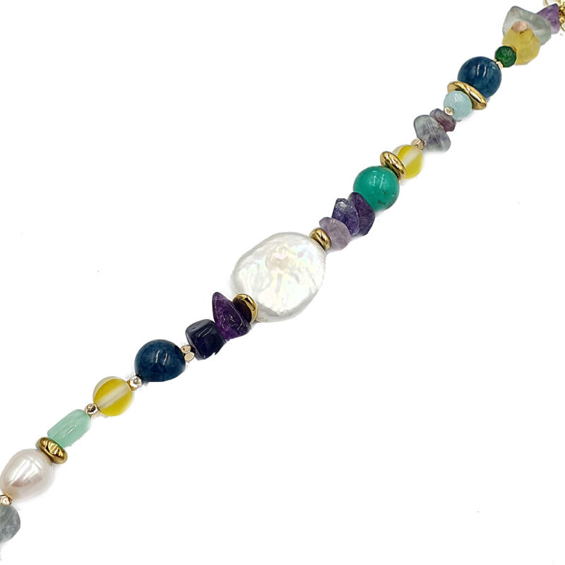 Beaded necklace with multicolored stones and a large white baroque pearl centerpiece on a diagonal strand.