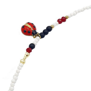 Delicate beaded bracelet featuring white round beads, a red enamel ladybug charm, and gold accents with darker navy beads.