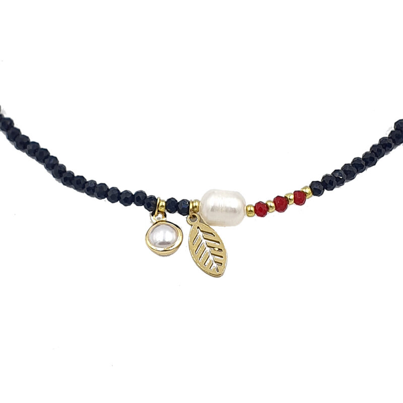 Beaded necklace with gold leaf charm, a pearl bead, and red and gold spacers on a black bead strand.