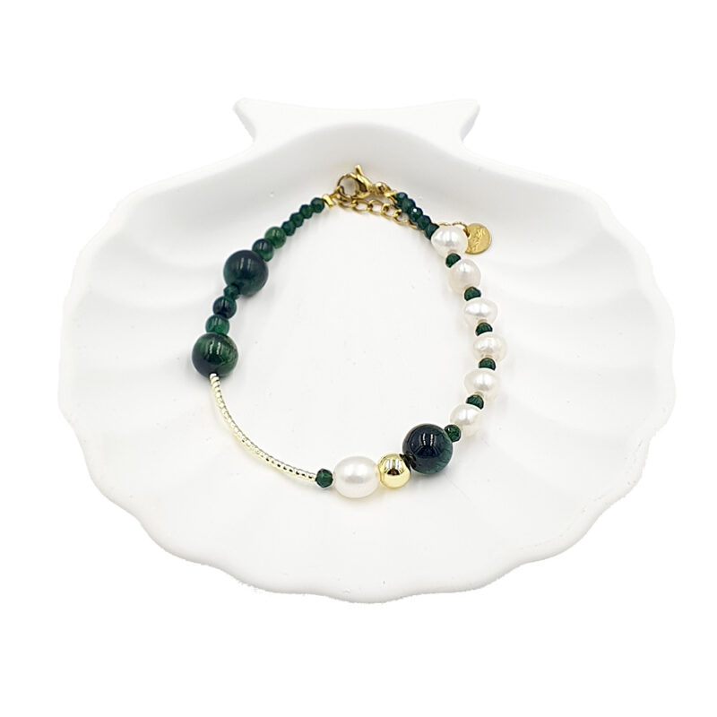 Bracelet with dark green beads and white freshwater pearls, gold spacers and clasp, arranged in a partial circle on a white shell dish.