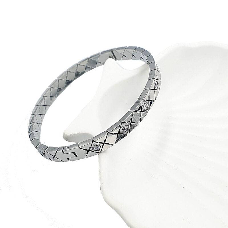 Βραχιόλι χειροπέδα ασημί με στρας 2 - bijouxbijoux Silver-toned bracelet with square, interlocking links and small diamonds, displayed on a white shell-shaped stand.