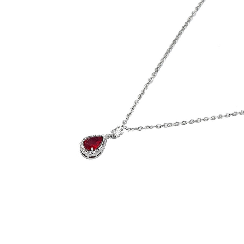 Silver chain necklace with a pear-shaped red gemstone pendant surrounded by small diamonds on a pavé halo