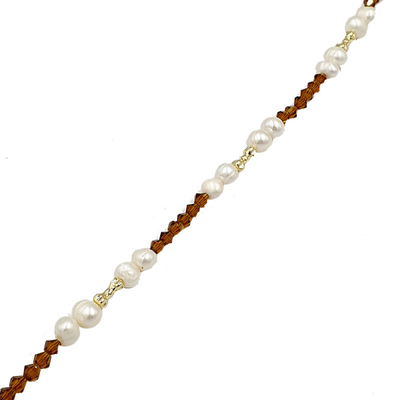 Beaded necklace with white pearls, brown faceted beads, and gold spacers laid diagonally.