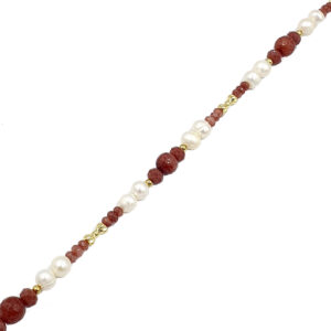 Beaded necklace with alternating red and white pearls and gold spacers laid diagonally across a white background.